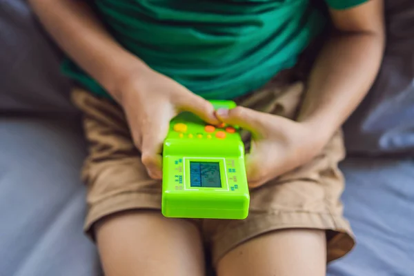 Young boy playing a tetris game. Old school portable game console, electronic retro pocket toy with monochrome display — Stock Photo, Image