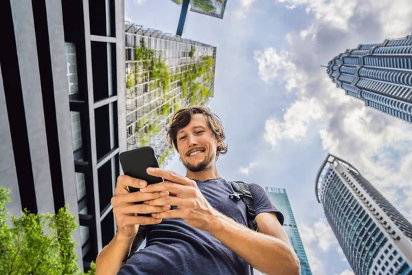 男子使用地图应用程序在智能手机上的摩天大楼背景 — 图库照片