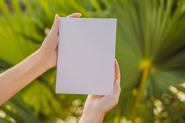 Womens hands in a tropical background holding a signboard paper, mockup — Stock Photo, Image