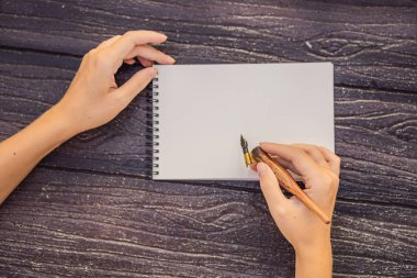 Womens hands in a wooden background holding a signboard, drawing block, paper, mockup