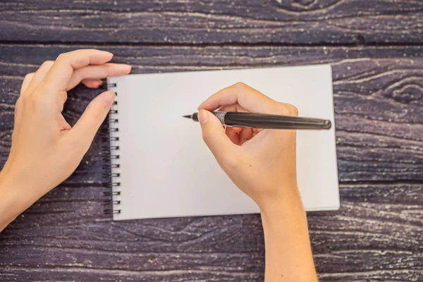 Vrouwen handen in een houten achtergrond met een bord, tekenblok, papier, mockup — Stockfoto