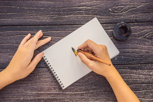 Vrouwen handen in een houten achtergrond met een bord, tekenblok, papier, mockup — Stockfoto