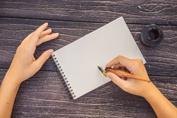 Womens hands in a wooden background holding a signboard, drawing block, paper, mockup