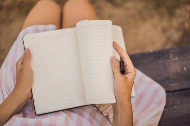 Womens hands in a tropical background holding a signboard, drawing block, paper, mockup