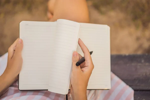 Manos de mujer en un fondo tropical sosteniendo un letrero, bloque de dibujo, papel, maqueta —  Fotos de Stock