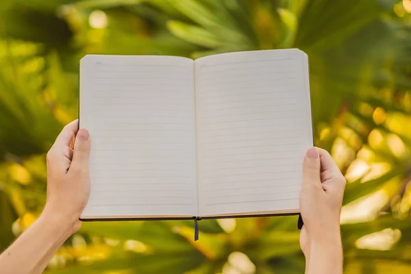 Womens hands in a tropical background holding a signboard, drawing block, paper, mockup