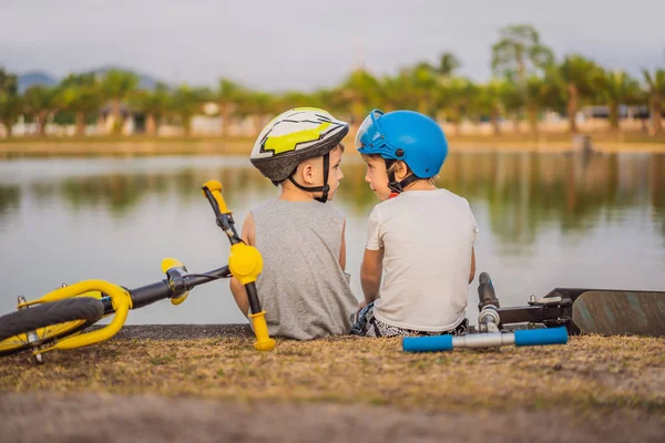 Dva chlapci sedí na břehu jezera po jízdě na kole a skútru — Stock fotografie