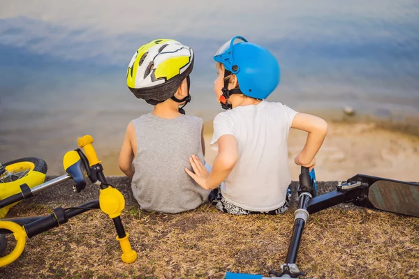 İki erkek bir bisiklet ve scooter sürdükten sonra göl kıyısında oturup — Stok fotoğraf