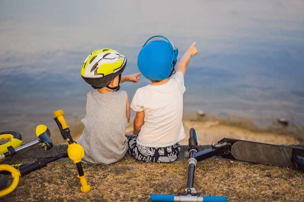 İki erkek bir bisiklet ve scooter sürdükten sonra göl kıyısında oturup — Stok fotoğraf