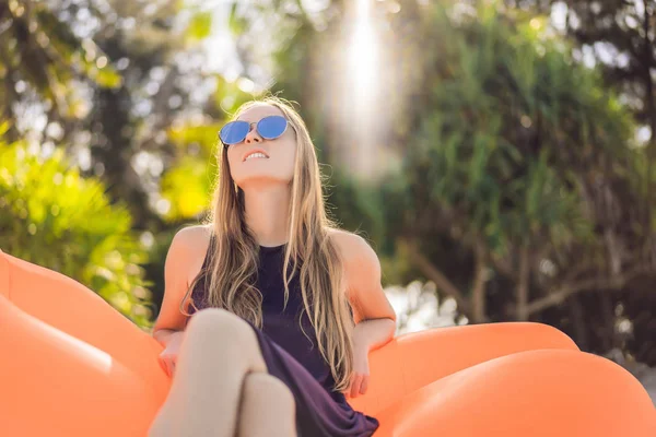 Sommer-Lifestyle-Porträt eines hübschen Mädchens auf dem orangefarbenen aufblasbaren Sofa am Strand der tropischen Insel. sich entspannen und das Leben auf dem Luftbett genießen — Stockfoto