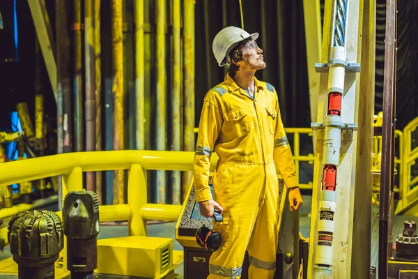Giovane in uniforme da lavoro gialla, occhiali e casco in ambiente industriale, piattaforma petrolifera o impianto a gas liquefatto — Foto Stock
