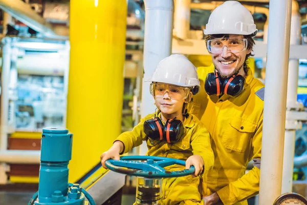 Mladý muž a malý chlapec jsou oba ve žluté pracovní uniformě, brýlích a helmě v průmyslovém prostředí, ropné plošině nebo v plynárně — Stock fotografie