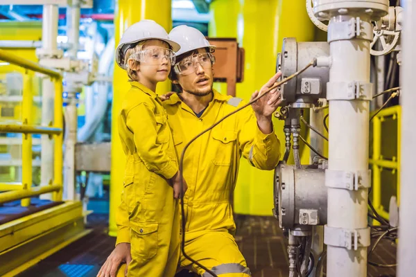 Il giovane e un bambino sono entrambi in uniforme da lavoro gialla, occhiali e casco in un ambiente industriale, piattaforma petrolifera o impianto di gas liquefatto — Foto Stock