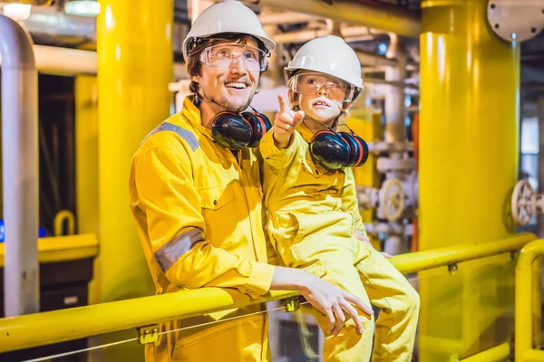 Il giovane e un bambino sono entrambi in uniforme da lavoro gialla, occhiali e casco in un ambiente industriale, piattaforma petrolifera o impianto di gas liquefatto — Foto Stock