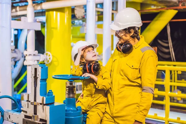 Joven y un niño pequeño están ambos en un uniforme de trabajo amarillo, gafas, y casco en un entorno industrial, Plataforma de petróleo o planta de gas licuado — Foto de Stock