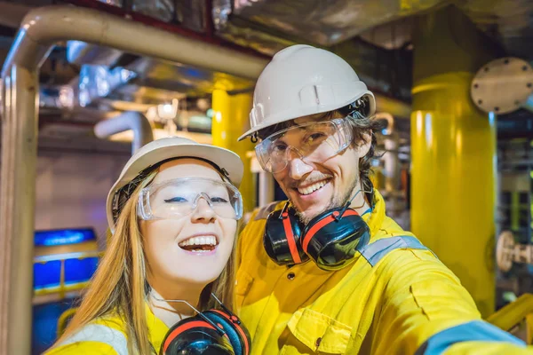 Hombre y mujer en uniforme de trabajo amarillo, gafas y casco en un entorno industrial, plataforma petrolera o planta de gas licuado — Foto de Stock