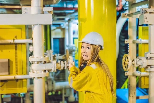 Mujer joven en uniforme de trabajo amarillo, gafas y casco en ambiente industrial, plataforma petrolera o planta de gas licuado — Foto de Stock