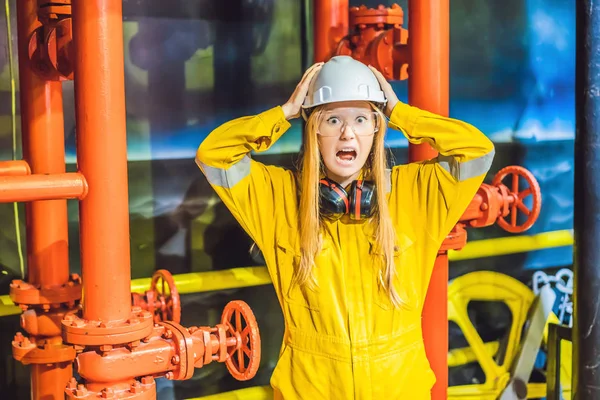 Mujer joven en uniforme de trabajo amarillo, gafas y casco en ambiente industrial, plataforma petrolera o planta de gas licuado — Foto de Stock