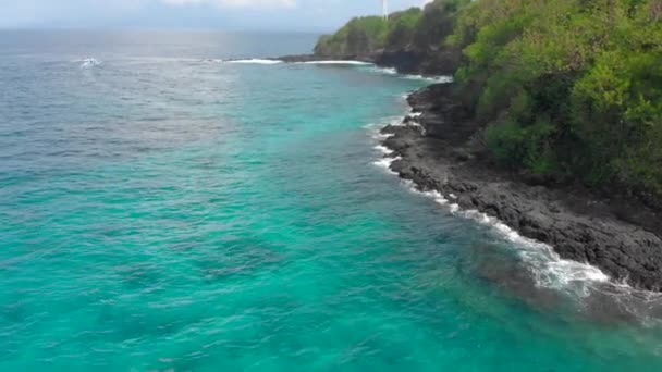 Vzdušný záběr na fantastickou pláž modré laguny na ostrově Bali s křišťálově průzračnou modrou vodou a bílým pískem obklopeným neuvěřitelnými černými sopečnými skalami — Stock video