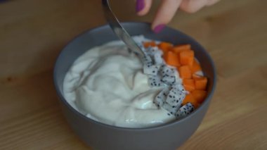Papaya, ejderha meyve, granola, kurutulmuş kiraz ve kabak çekirdeği ile bir smoothie kase yapma sürecinin Closeup çekim