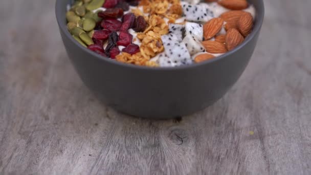 Tiro de close-up de uma tigela de smoothie com mamão, fruta de dragão, granola, cereja seca e sementes de abóbora. Conceito de pequeno-almoço saudável — Vídeo de Stock