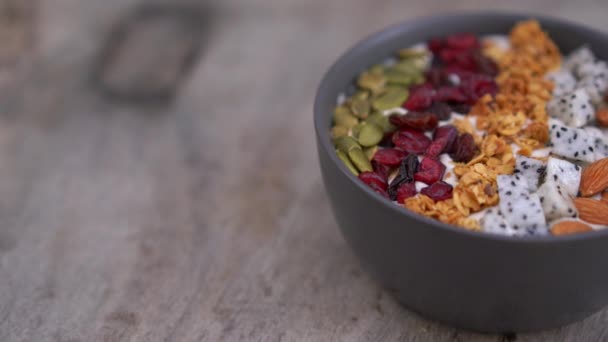 Närbild skott av en smoothie skål med papaya, Dragon frukt, granola, torkade körsbär, och pumpafrön. Hälsosamt frukost koncept — Stockvideo