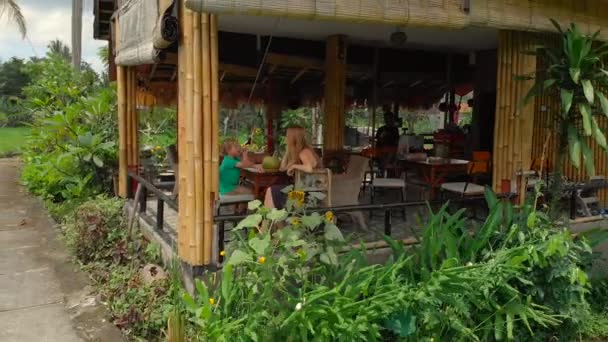 Снимок с воздуха женщины и ее сына, сидящих в кафе в окружении красивых рисовых полей — стоковое видео