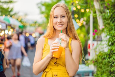 Asya pazarında portakal suyu içen bir kadın.