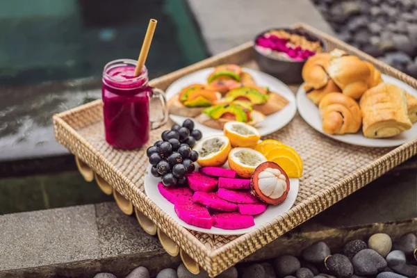 早餐在托盘上，有水果、包子、鳄梨三明治、冰沙碗。夏季健康饮食，素食早餐。美味度假理念 — 图库照片