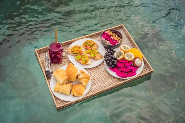 Bandeja de desayuno en la piscina, desayuno flotante en batidos de lujo y plato de frutas, batido en la piscina del hotel. Dieta exótica de verano. Estilo de vida tropical de playa. Tendencia Bali — Foto de Stock