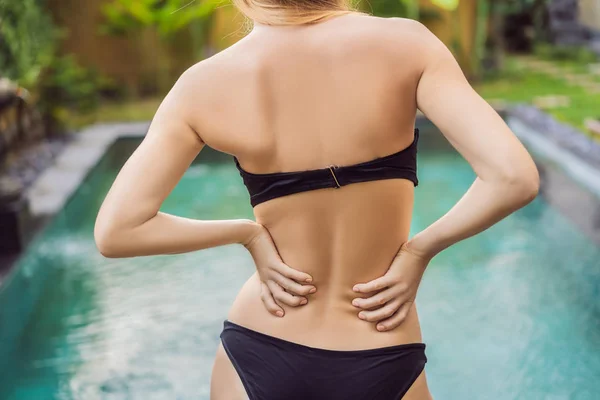女性の背中はプールの背景に痛い。プールは腰痛に役立ちます — ストック写真