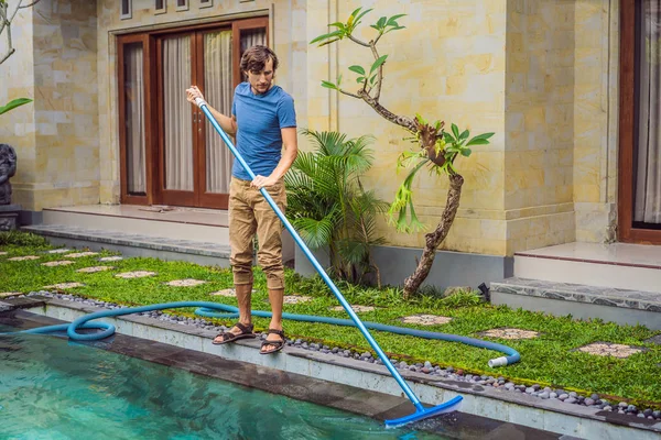 Limpiador de la piscina. Hombre de camisa azul con equipo de limpieza para piscinas. Servicios de limpieza de piscinas — Foto de Stock