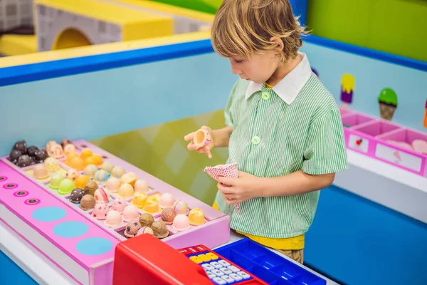 Um menino joga em uma cozinha de brinquedo, faz um sorvete de brinquedo — Fotografia de Stock