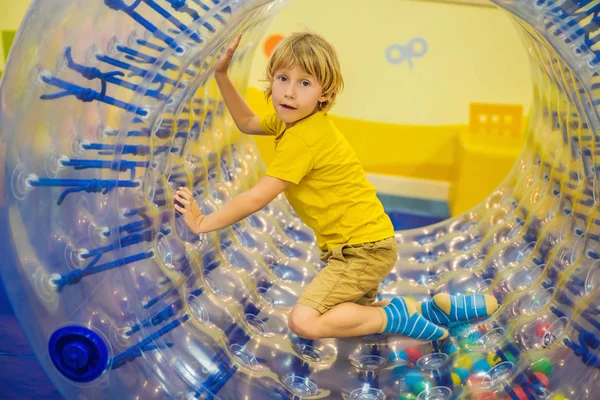 Aranyos kisfiú, játszik a Zorb egy gördülő műanyag palack gyűrű egy lyuk a közepén, intdoor — Stock Fotó