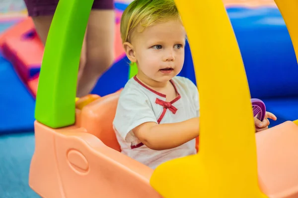 Мальчик едет на игрушечной красочной машине — стоковое фото