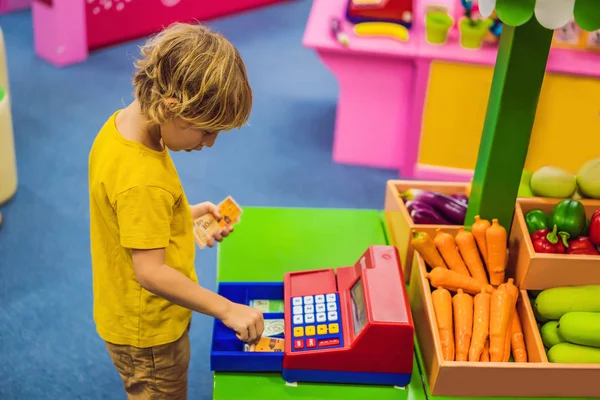 Der Junge spielt mit der Kinderkasse. Finanzielle Kompetenz für Kinder — Stockfoto