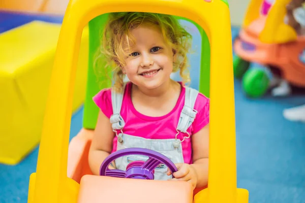 Küçük kız bir oyuncak renkli araba sürmek — Stok fotoğraf