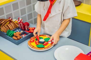 Çocuk oyuncak mutfakta oynuyor, pizza pişiriyor.