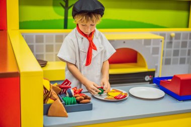 Çocuk oyuncak mutfakta oynuyor, pizza pişiriyor.