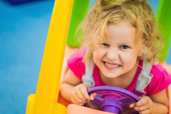 Küçük kız bir oyuncak renkli araba sürmek — Stok fotoğraf