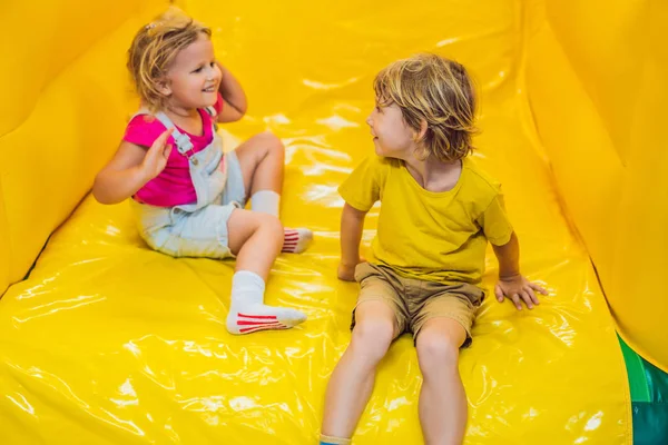 Un niño y una niña viajan desde una diapositiva inflable — Foto de Stock