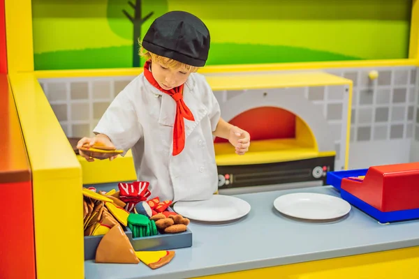 Der Junge spielt in der Spielzeugküche, kocht eine Pizza — Stockfoto