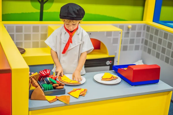 Der Junge spielt in der Spielzeugküche, kocht eine Pizza — Stockfoto