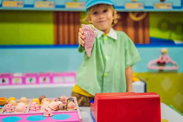 Ein Junge spielt in einer Spielzeugküche, macht ein Spielzeug-Eis — Stockfoto