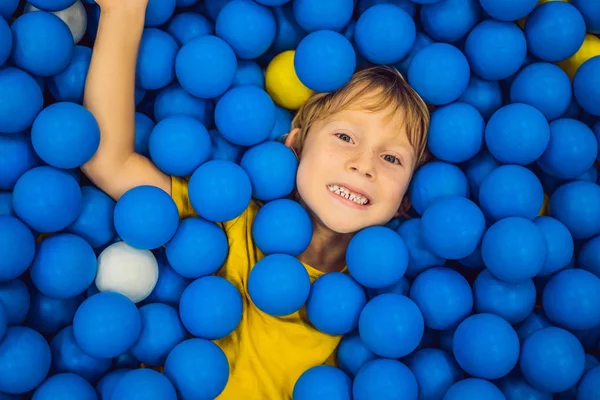 Child playing in ball pit. Colorful toys for kids. Kindergarten or preschool play room. Toddler kid at day care indoor playground. Balls pool for children. Birthday party for active preschooler