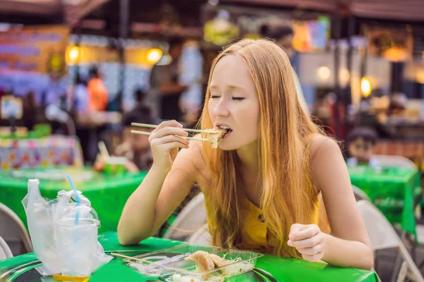 Feliz bonito gilr comer comida de rua e olhando agradável em uma pequena feira tradicional — Fotografia de Stock