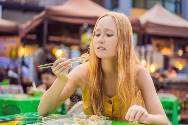 Счастливый симпатичный жар ест уличную еду и выглядит весело на традиционной маленькой ярмарке — стоковое фото