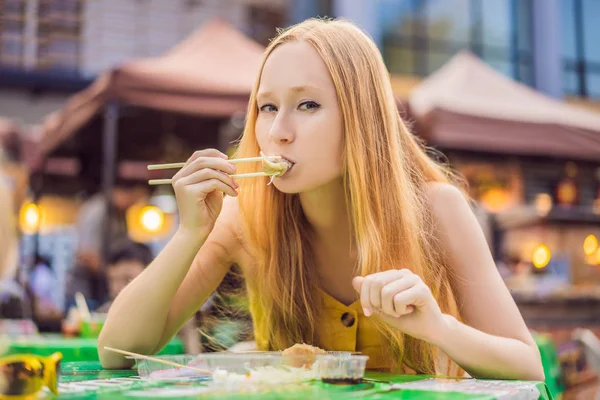 Feliz bonito gilr comer comida de rua e olhando agradável em uma pequena feira tradicional — Fotografia de Stock