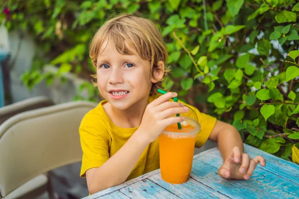 Dulce niño caucásico, comiendo panqueques y bebiendo jugo de naranja — Foto de Stock