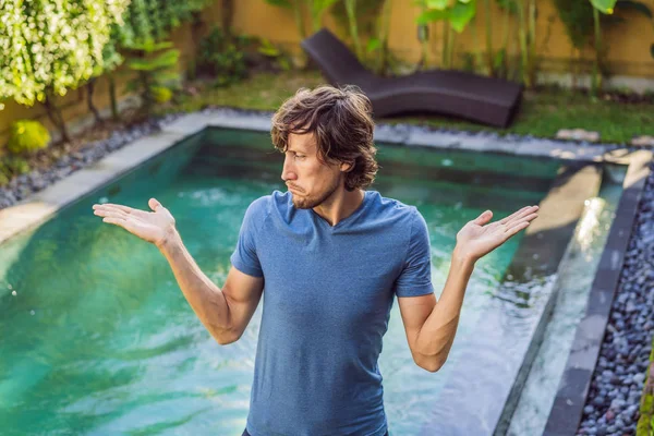 L'uomo sceglie le sostanze chimiche per la piscina. Servizio piscina e attrezzature con prodotti chimici per la pulizia e utensili — Foto Stock